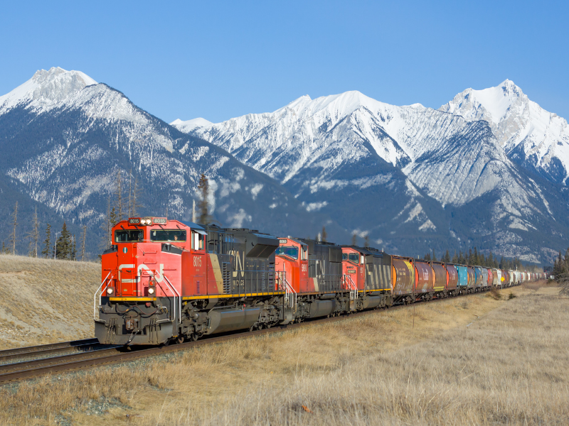 Freight train moving through a mountain corridor, illustrating transportation risk in paper supply chains.