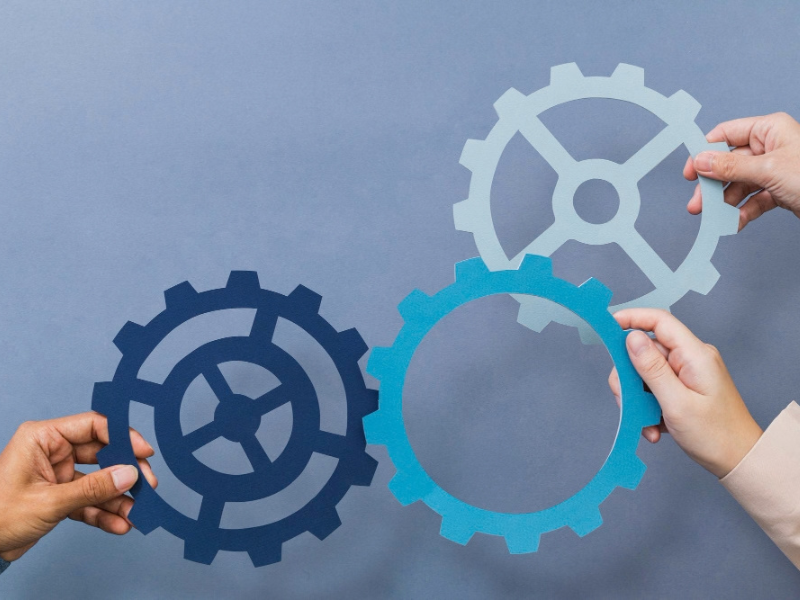 Hands arranging interlocking gears, symbolizing process control and workflow integration in modern press operations.