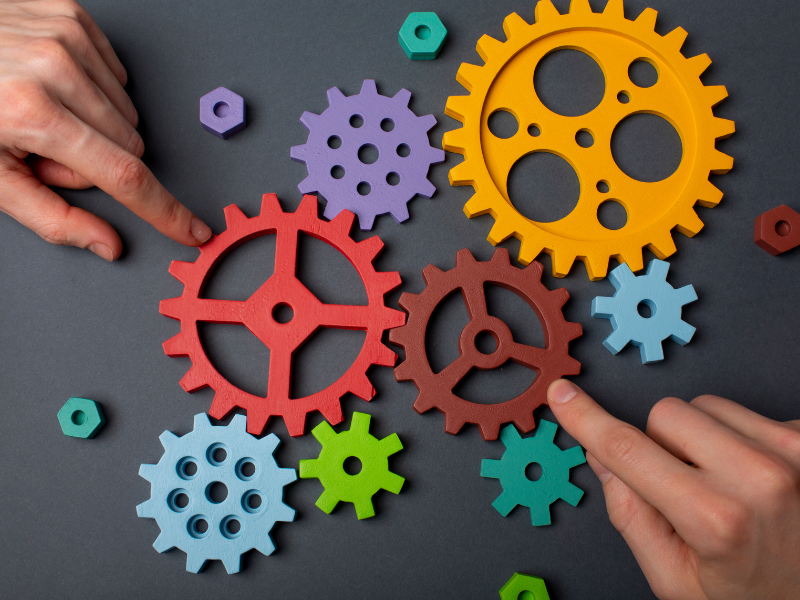 What Independent Printers Can Learn From Industry Consolidation Hands pointing to interlocking gears, illustrating how independent printers can respond to industry consolidation.
